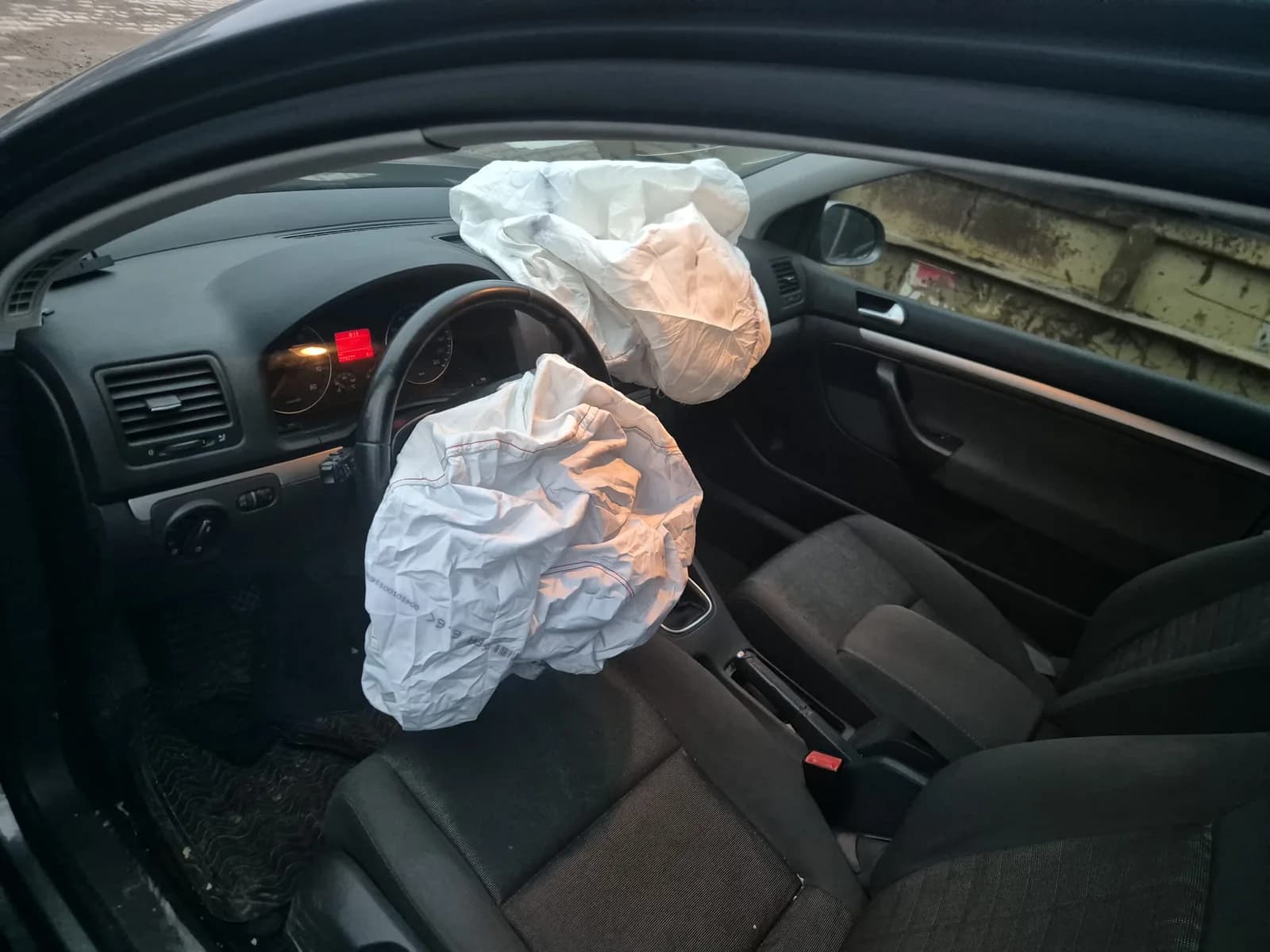 Fahrer- und Beifahrerairbag eines Pkw nach dem Auslösen, Blick durch die geöffnete Fahrertür
