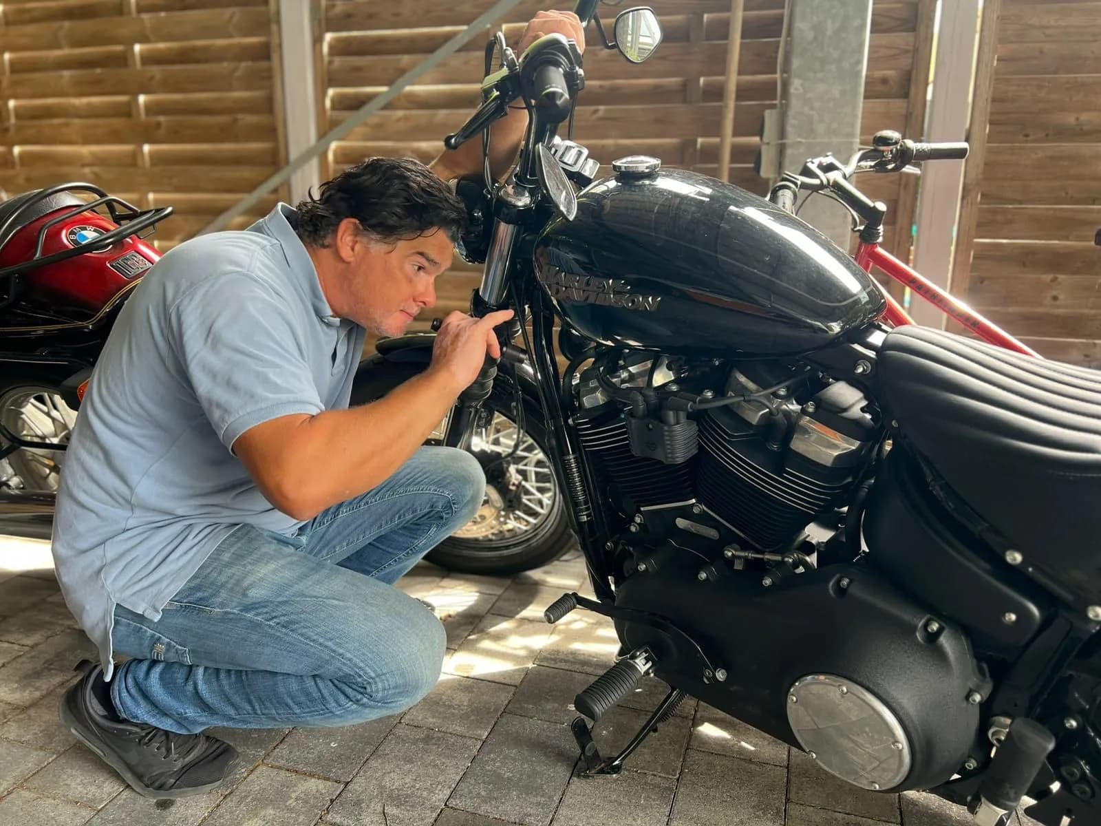 Ferdinand Wolf kniet neben einem Motorrad und misst am Tank
