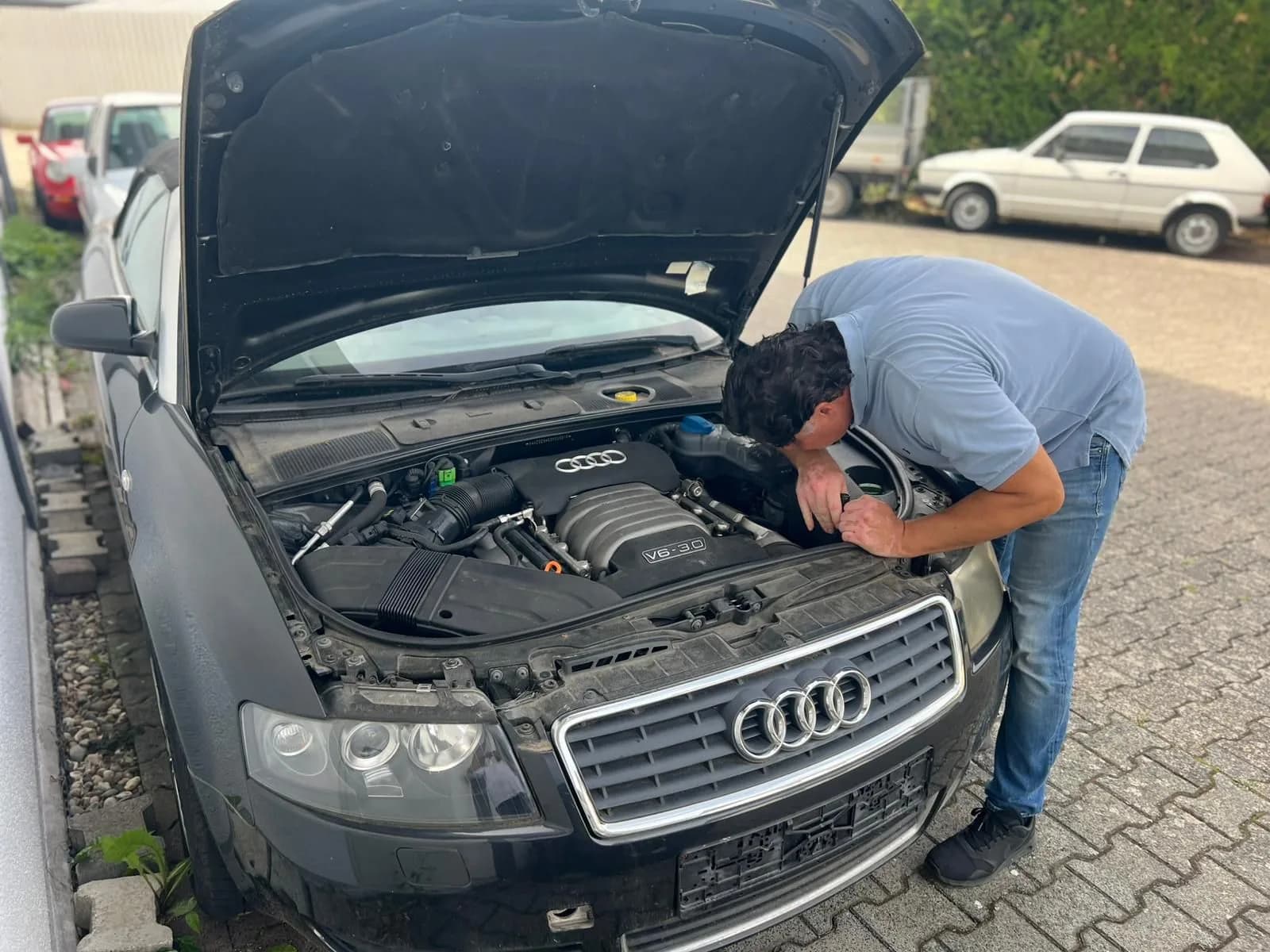 Ferdinand Wolf untersucht den Motorraum einer dunklen Limousine