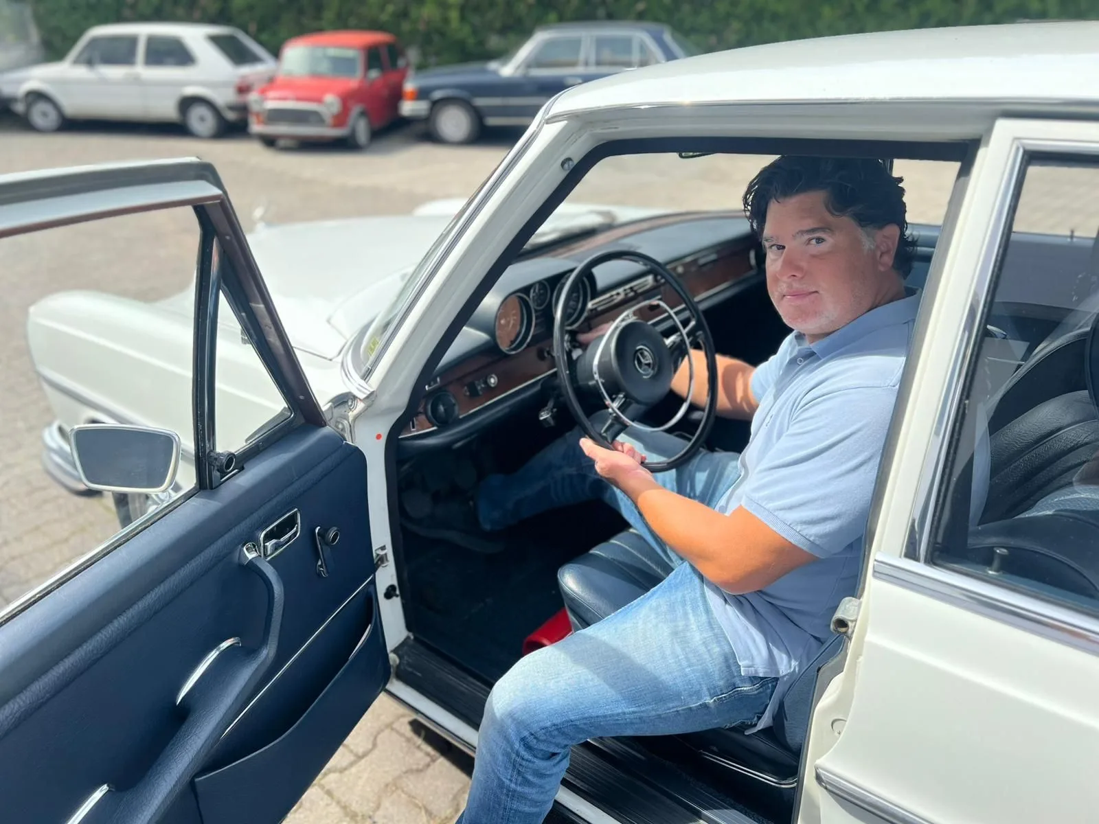 Ferdinand Wolf sitzt am Steuer einer weißen Mercedes-Limousine aus den Sechzigern