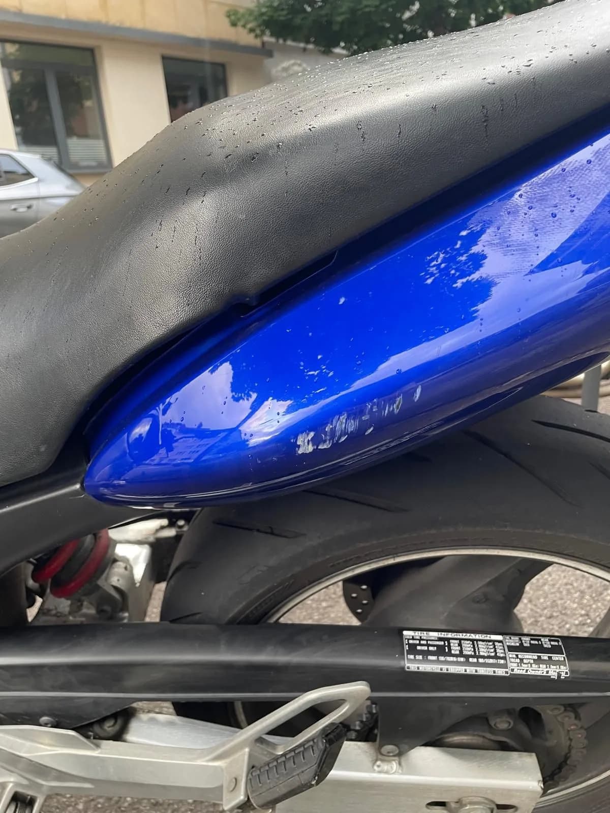 Heckverkleidung eines blauen Motorrads mit Schleifspuren und Lackabrieb